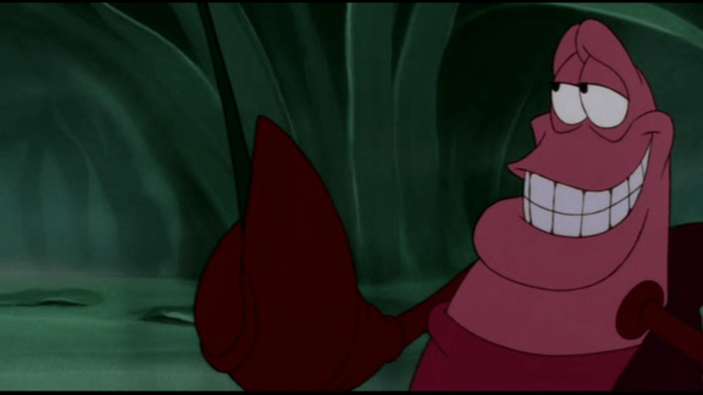 Il Granchio rosso Sebastian circondato da piante acquatiche. Ha la chela sinistra verso l'alto ed è voltato leggermente verso destra con un'espressione concentrata.